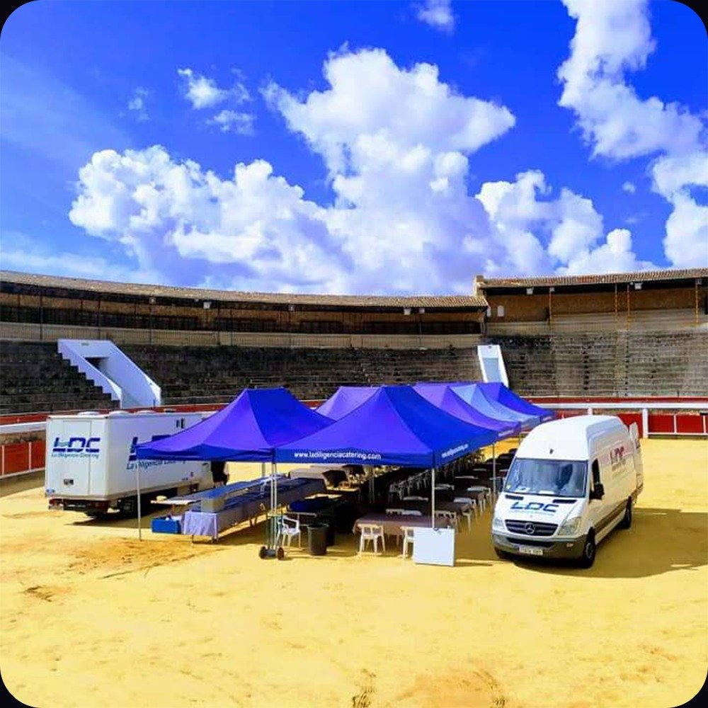 Vehículos y carpas de La Diligencia Catering montados en una plaza de toros